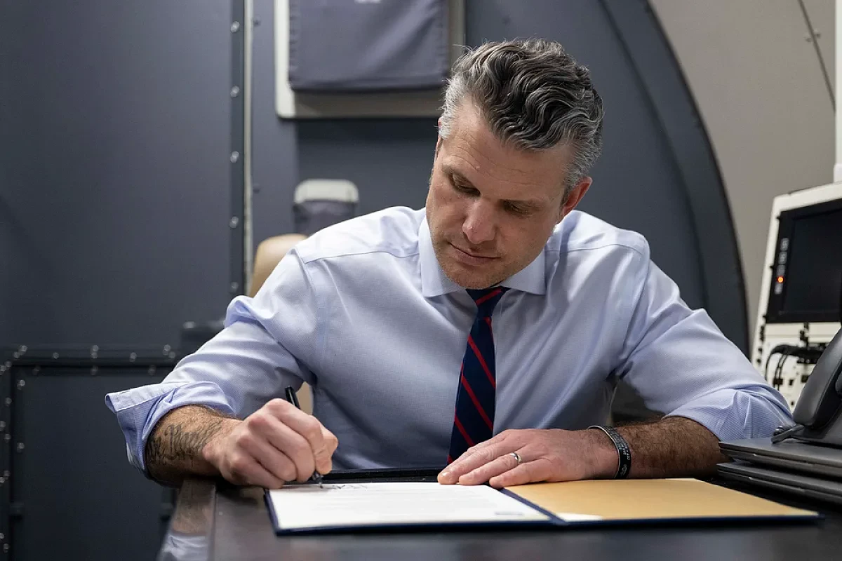 Secretary of Defense Pete Hegseth signs a memorandum aboard an E-4B Nightwatch aircraft